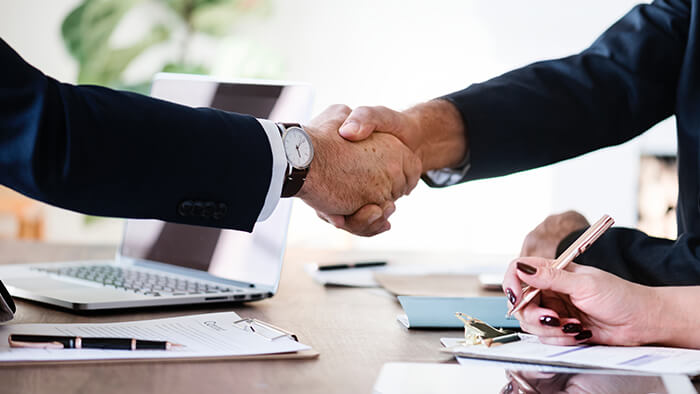 Two Business Men Shaking Hands Over Desk